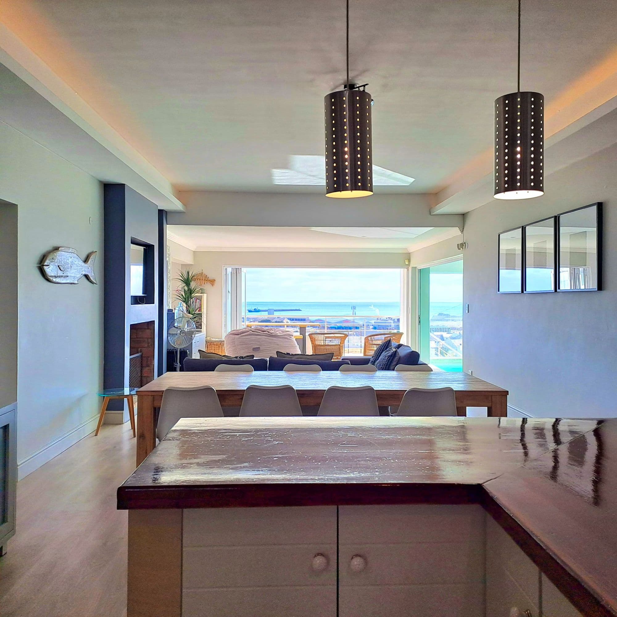 Living room opening onto the balcony, sea visible through the bifold doors
