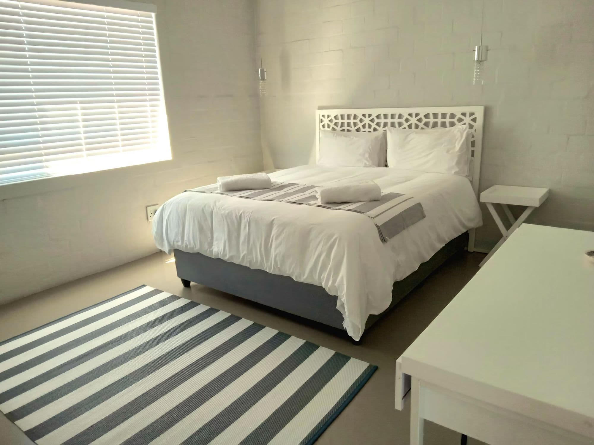 One of the villa's five bedrooms, with a striped rug and soft daylight