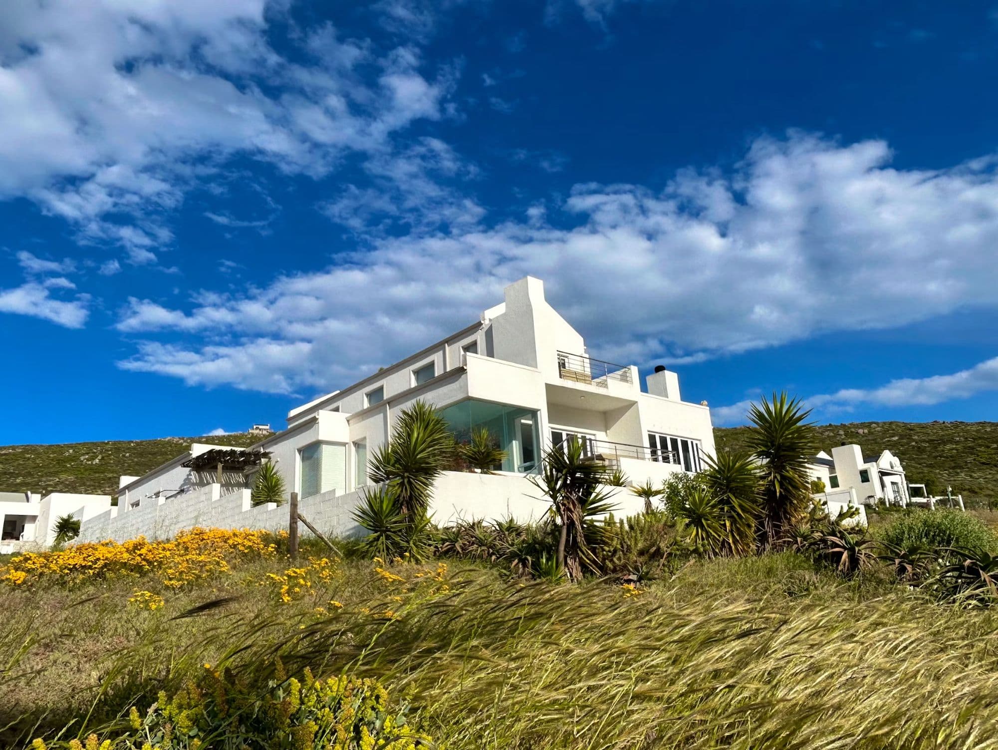 Bay View Villa on its hillside, fynbos in bloom, St Helena Bay behind it