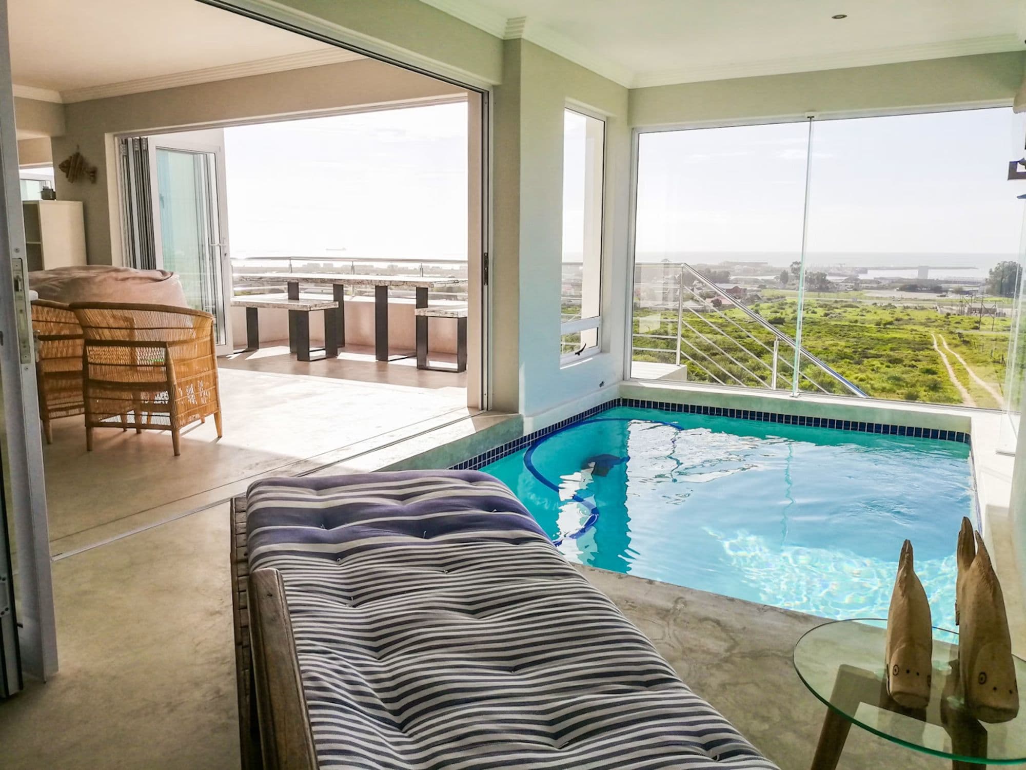 The glass-walled pool opening onto the balcony, with the bay beyond