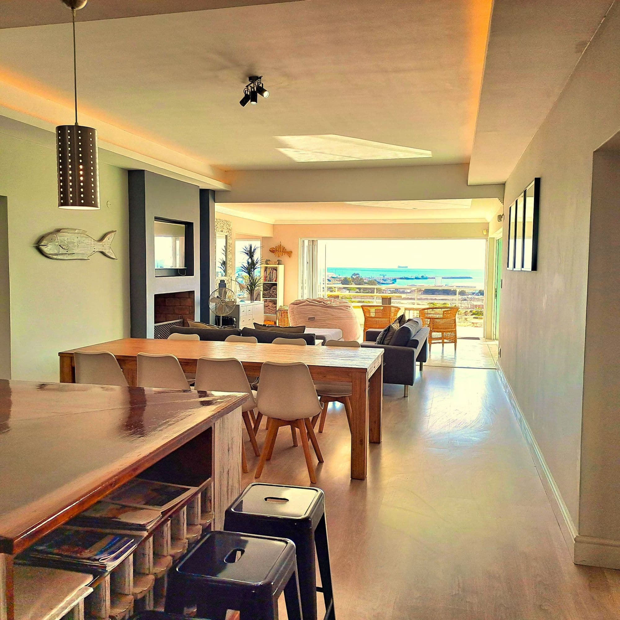 The open-plan kitchen and dining table, with the bay visible through the doors beyond